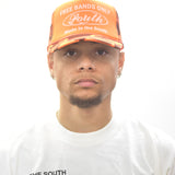 Model wearing an orange cap trucker hat and white signature t-shirt