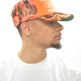 Model wearing an orange camo trucker hat